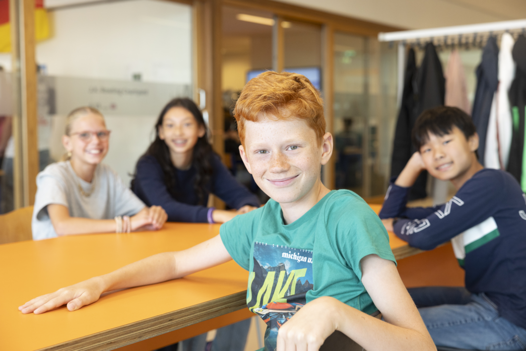 Leerling van Melanchthon Bergschenhoek zittend aan tafel met een groepje leerlingen op de achtergrond.