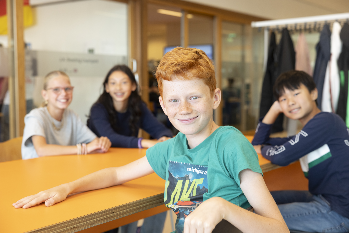 Leerling van Melanchthon Bergschenhoek zittend aan tafel met een groepje leerlingen op de achtergrond.