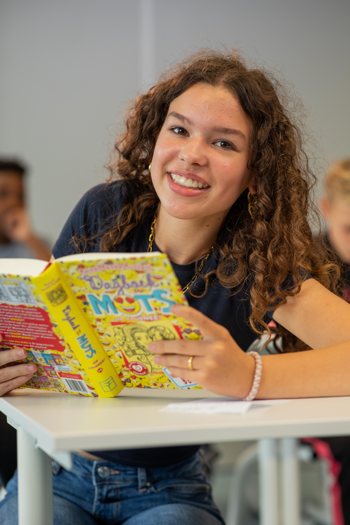Leerling van Melanchthon Berkroden kijkt lachend in de camera met een boek in haar hand.