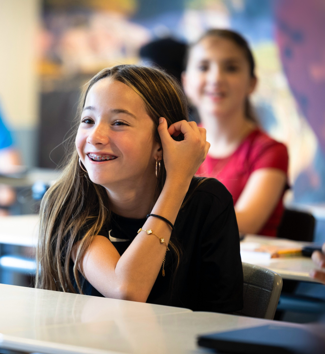 Lachende leerling van Melanchthon Mavo Schiebroek, zittend in de klas. Ze doet nonchalant haar achter haar oor.