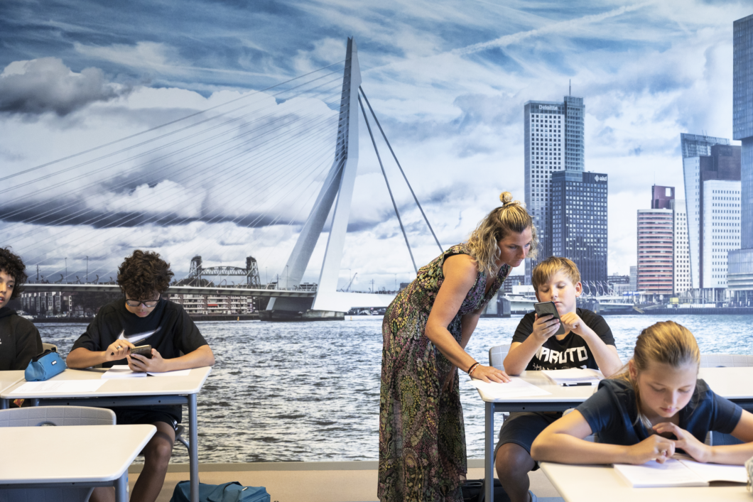 Collega en leerling van Melanchthon Mavo Schiebroek kijken wijs de camera in. De leerling leunt nonchalant op de docent.