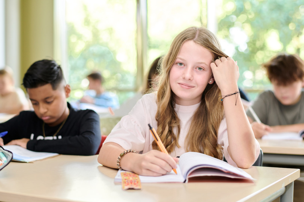 Leerling in de klas met een schrift voor zich, in haar hand heeft zij een balpen.